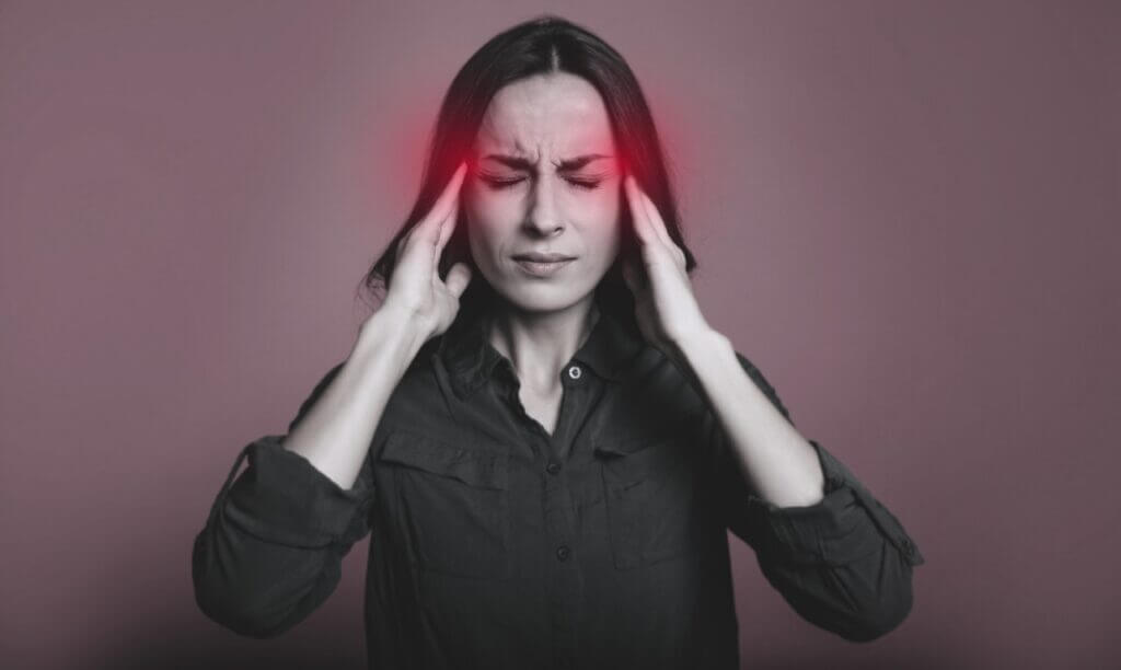 Patient holding their head in discomfort from a migraine